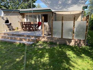 A backyard with a covered patio, a grill, and a dining area.