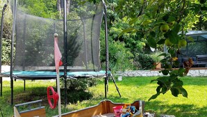 A wooden boat-shaped sandbox with a paddle, surrounded by pebbles and filled with sand.