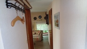 A hallway leading to a living room with a sofa and a dining table. -  Apartments directly on the North Sea in Schleswig-Holstein (Friedrichskoog)