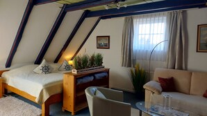 Una stanza accogliente con un letto, un comodino in legno, una sedia, un divano e una finestra con tende.