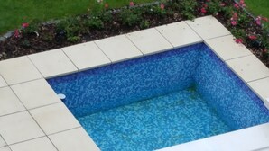 Una piscina con revestimiento interior de mosaico azul y borde exterior de azulejos blancos.