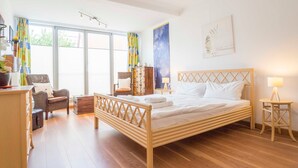 Um quarto com uma cama de madeira, uma cadeira, uma escrivaninha e um guarda-roupa.