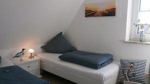 A bedroom with a bed, a nightstand, a lamp, a window with a view, and a painting on the wall.