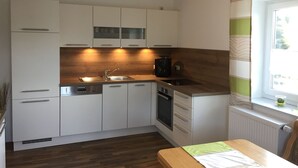 A modern kitchen with white cabinets, a wooden countertop, a built-in oven, and a window with a view of greenery. - Newly renovated apartment f. d. high standards in an idyllic secluded location (Zachenberg)