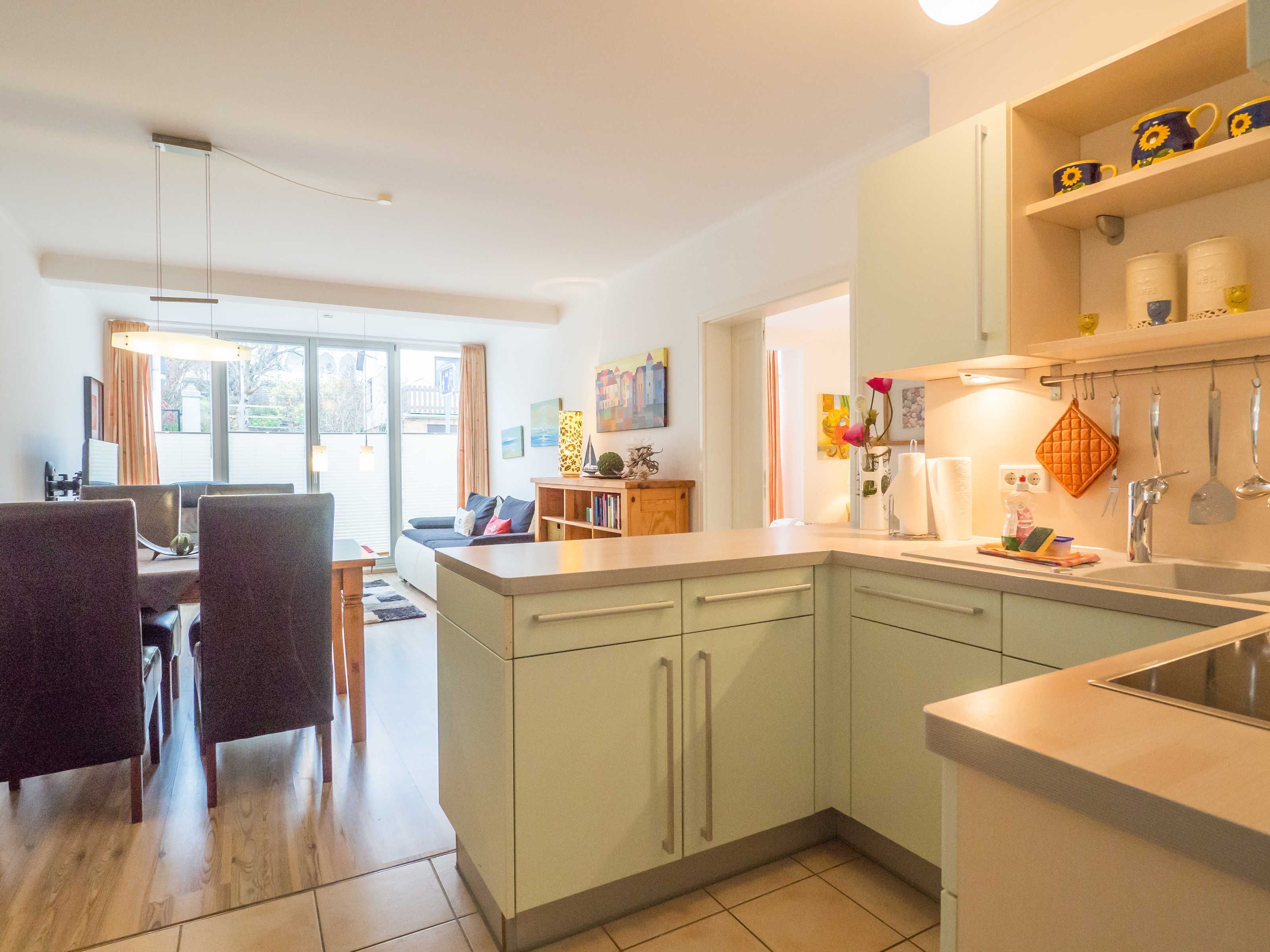 Une cuisine moderne avec un coin repas, comprenant un grand îlot central, des meubles de couleur claire et une vue sur l’extérieur.