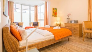 Ein Hotelzimmer mit einem großen Bett, einem kleinen Tisch, einem Sessel und einer Lampe sowie einem Radio.