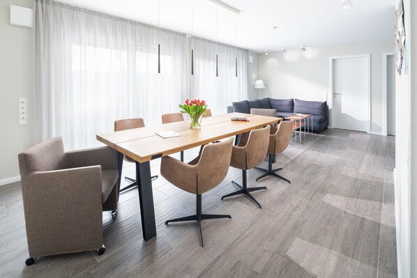 A modern living room with a dining area, featuring a wooden table, chairs, a sofa, and a coffee table. - Villa Rosch, WiFi, SKY HD, air-conditioned / ventilation / 4SZ / 2BZ / natural / luxury / (Norderney)