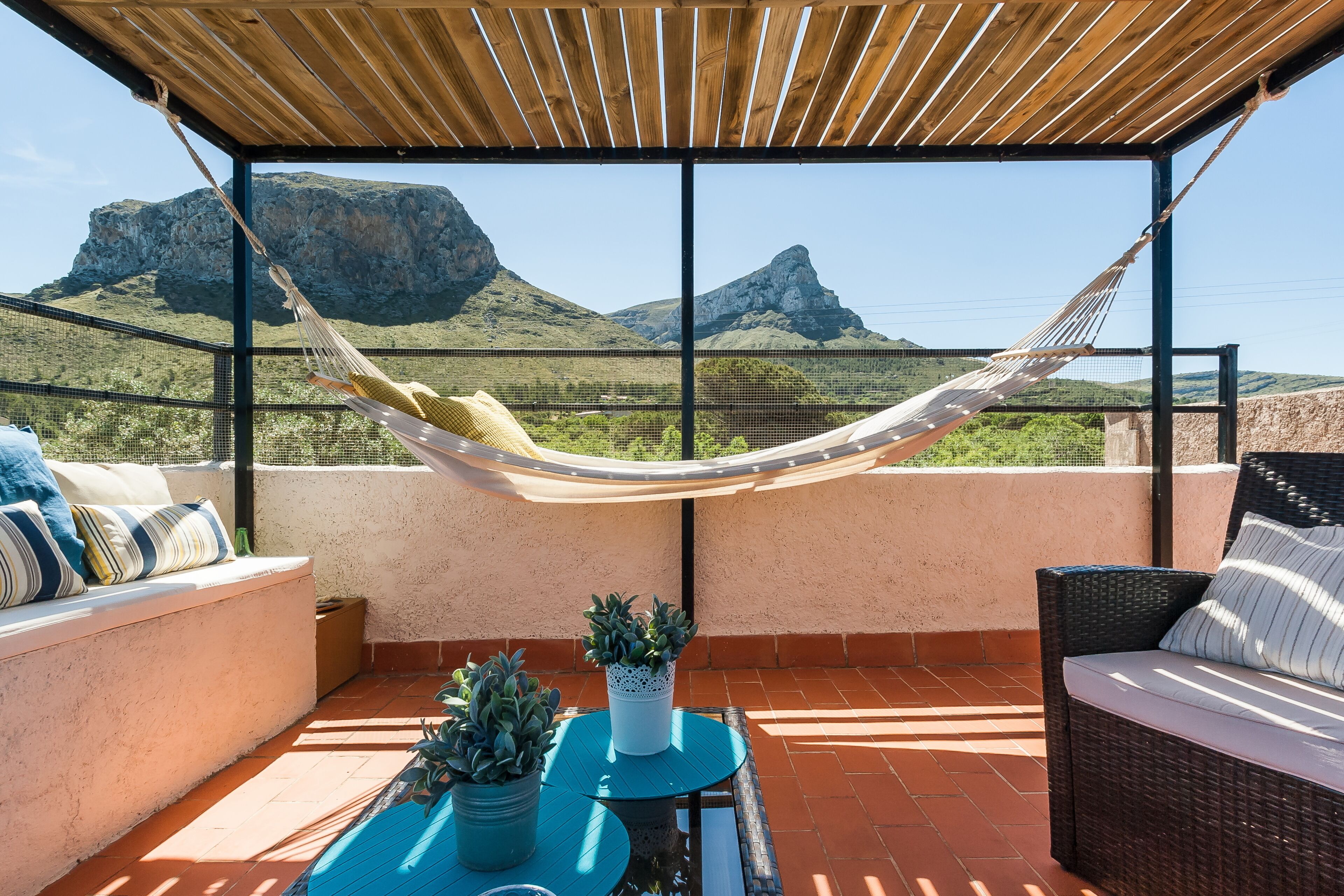 Terraço no telhado com rede, área de estar e plantas em vasos.