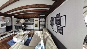 Ein modernes Wohnzimmer mit Fernseher, Sofa und Essbereich.