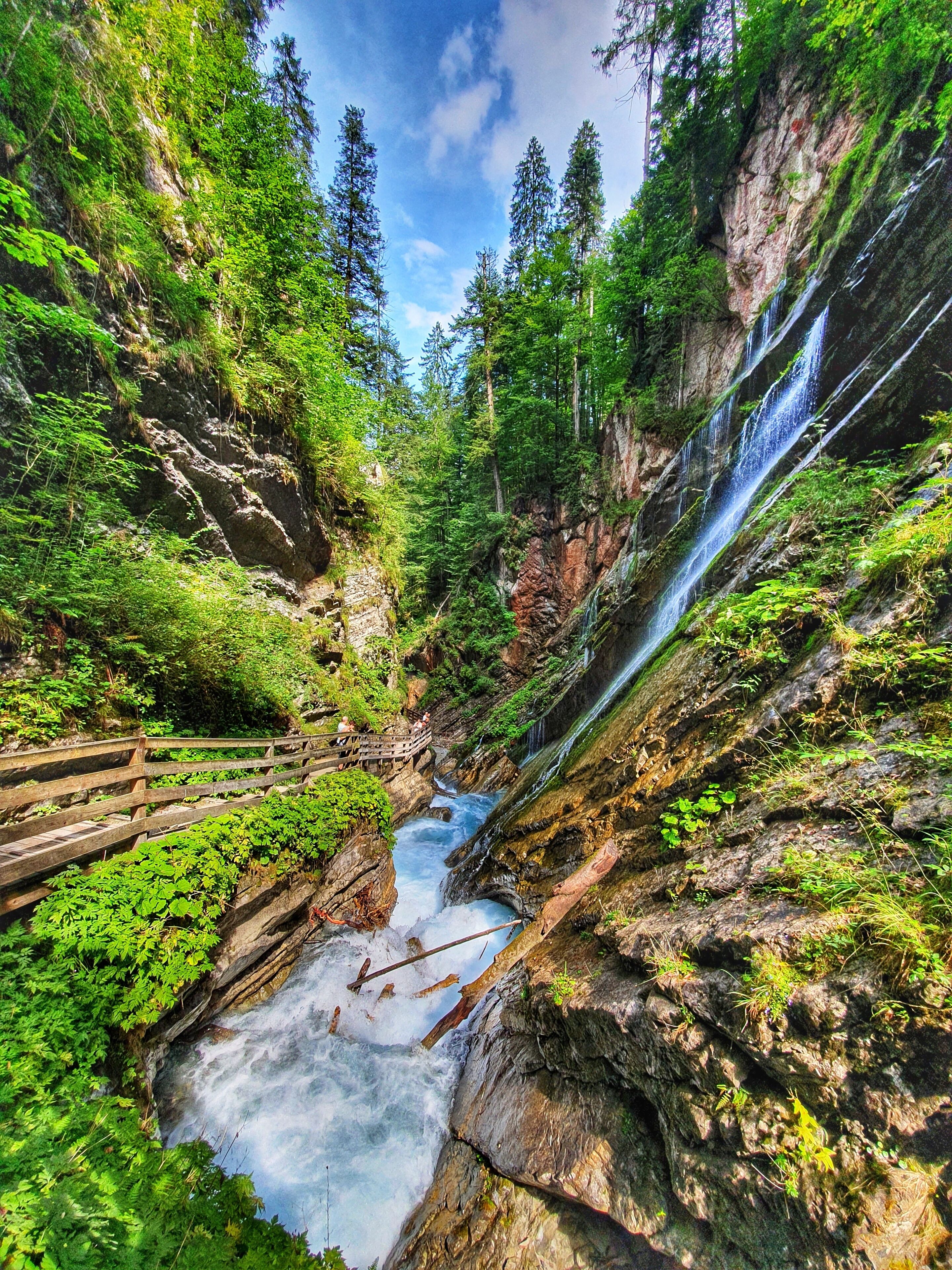 Ein Wasserfall, umgeben von üppiger Vegetation und felsigem Gelände.