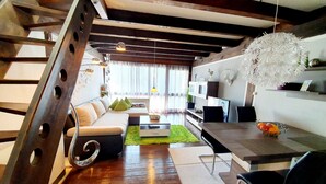 Ein modernes Wohnzimmer mit einer Holztreppe, einem Sofa, einem Couchtisch und einem Essbereich.