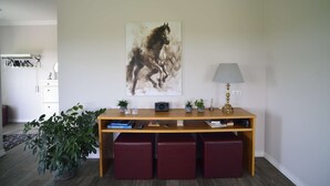 Ein Zimmer mit einem Holztisch, roten Sitzgelegenheiten, einer Wandlampe und einem großen abstrakten Gemälde.