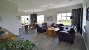 Ein geräumiges Wohnzimmer mit Essbereich, großen Fenstern und einem modernen Deckenstil.