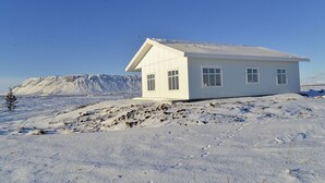 Ein weißes Gebäude mit Satteldach in einer verschneiten Landschaft.