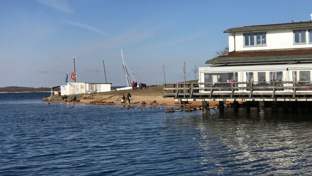 Une propriété située au bord de l’eau, dotée d’un quai, d’un bâtiment avec balcon et d’un petit bateau.