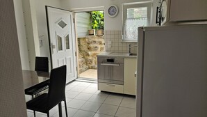 Eine kompakte Küche mit einem Bosch-Ofen, einer Spüle und einem Essbereich mit einem schwarzen Stuhl.