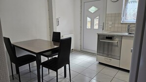 Eine kleine Küche mit Backofen von Bosch, einem Esstisch mit Stühlen und einem Fenster mit Blumenmuster-Vorhang.