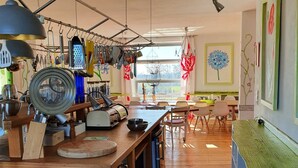 A kitchen with wooden countertops, hanging utensils, and a dining area with chairs and a table. - Room in an old manor with an artistic atmosphere (neukalen)