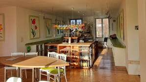 A spacious kitchen with wooden flooring, a central island, and a dining area with white chairs. - Room in an old manor with an artistic atmosphere (neukalen)