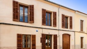 A building with multiple wooden shutters, a large arched door, and a small window. - Can Caragol (Sineu)