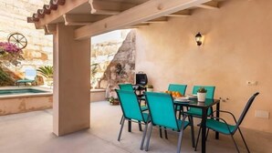 An outdoor patio with a table and chairs, a barbecue grill, and a view of a rocky landscape. - Can Caragol (Sineu)