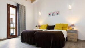 A bedroom with a double bed, two bedside tables, a nightstand, a window with blinds, and a wall-mounted artwork. - Can Caragol (Sineu)