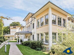 A multi-story building with a beige facade, large windows, and a covered entrance area. - Villas at Goethe Park, Villa Christiane, Whg. 04 - Lena - Villas at Goethe Park, Villa Christiane, Whg. 04 - Lena (Heringsdorf)