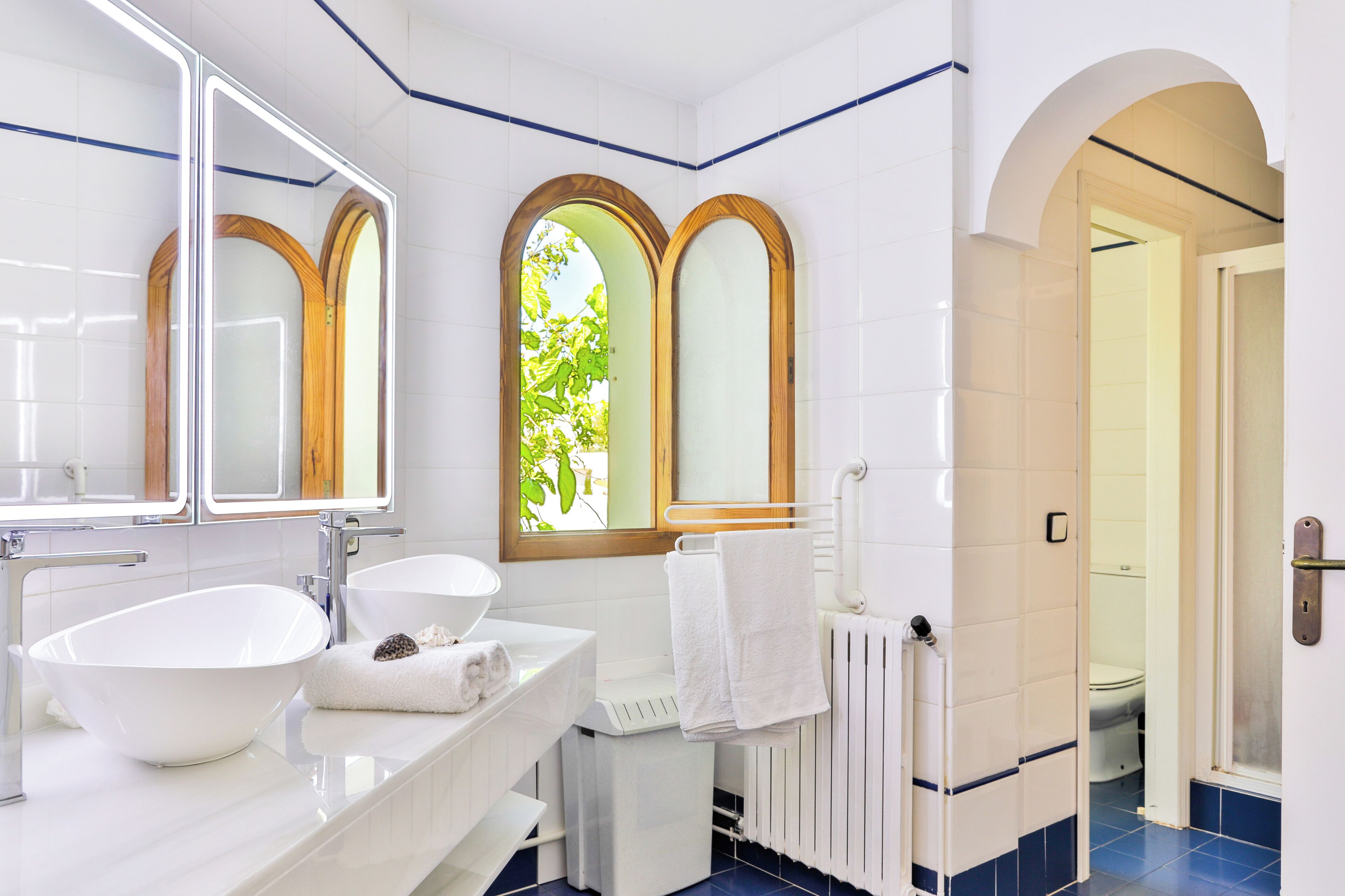 A modern bathroom with a large sink, mirror, and two vanity mirrors.