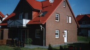 A two-story brick house with a red roof, satellite dish, and a garage.