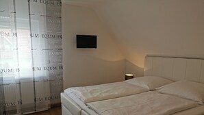 A bedroom with a bed, a bedside table, a lamp, and a TV mounted on the wall.