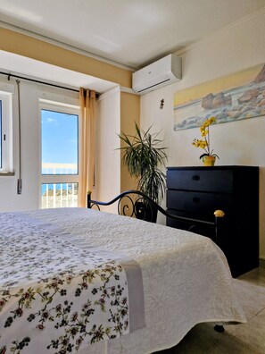 Quarto com cama, cômoda, planta em vaso e um quadro na parede.