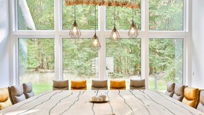 A dining room with a long table, multiple chairs, and hanging pendant lights. - Villa Thormarcon, Plauer See, 20 Gäste, Sauna+Pool (Malchow)