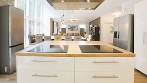 A modern kitchen with a central island, stainless steel appliances, and a large window providing natural light. - Villa Thormarcon, Plauer See, 20 Gäste, Sauna+Pool (Malchow)