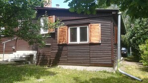 A log cabin with a window and a door, surrounded by greenery.