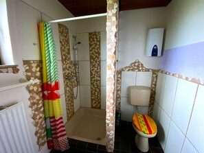 A bathroom with a shower, toilet, and a decorative shower curtain. - How in heaven, colorful house on a hill with stunning views of the Ederta (Hatzfeld)