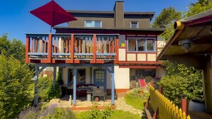 A two-story house with a balcony, a garden, and a red umbrella. - How in heaven, colorful house on a hill with stunning views of the Ederta (Hatzfeld)