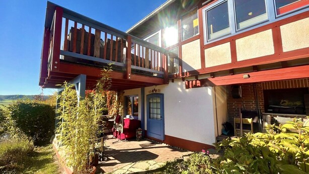 A two-story building with a balcony, a door, and a barbecue area. - How in heaven, colorful house on a hill with stunning views of the Ederta (Hatzfeld)