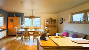 A cozy kitchen with wooden cabinets, a dining table with chairs, a laptop on the counter, and a window with a view of the outdoors. - How in heaven, colorful house on a hill with stunning views of the Ederta (Hatzfeld)