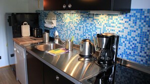 Uma cozinha moderna com eletrodomésticos de aço inoxidável, um painel de azulejos em azul e prateleiras de madeira.