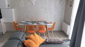 A modern living room with a grey sectional sofa, orange cushions, and a striped pillow. - Lovely vacation home, De Haan, 6 pers., completely renovated, child-friendly (De Haan)