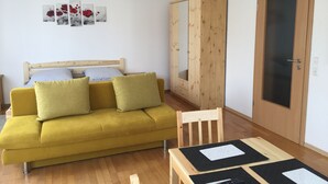 A room with a wooden bed, a yellow sofa, a wooden wardrobe, and a door with a frosted glass panel.