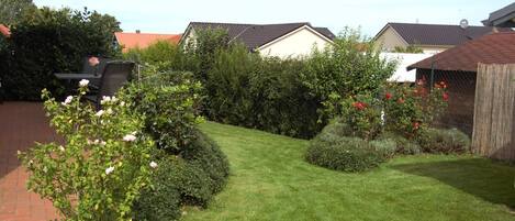 A well-maintained garden with a variety of plants and flowers, a neatly trimmed lawn, and a wooden fence.
