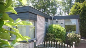 Ein modernes, zweistöckiges Haus mit Ziegelaußenwand, großen Fenstern und einem Holzzaun.