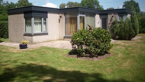 Ein zweistöckiges Haus mit Backsteinfassade, einer Veranda und einem gepflegten Rasen.