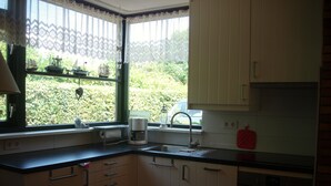 Eine kleine Küche mit Fenster, einer Kaffeemaschine und einem Spülbecken.