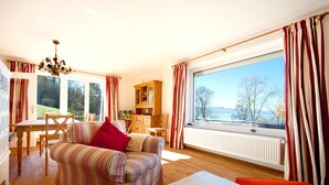 A cozy living room with a sofa, a dining table, and a view of a lake.