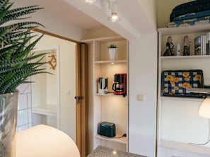 Una kitchenette con cafetera, tostadora y una planta en maceta.