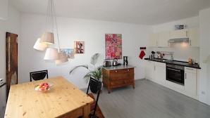 Una cocina moderna con armarios blancos, una mesa de comedor de madera y una cafetera.