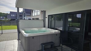 A hot tub on a covered patio with a view of buildings in the background.