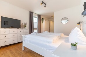 Une chambre d’hôtel moderne, dotée d’un grand lit, d’une télévision, d’une commode et d’un miroir.